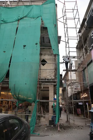 Pieces of debris falling down while pedestrians walk beneath....